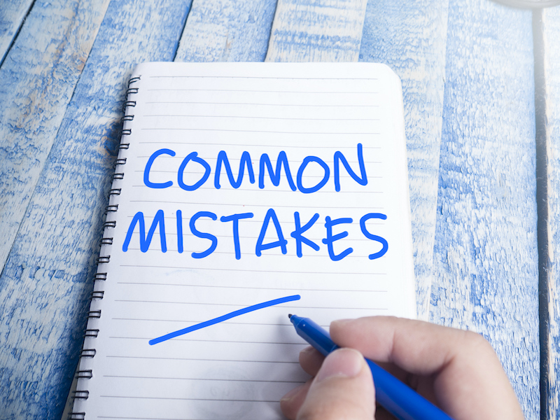 Hand written blue letters spelling the words common mistakes on a lined paper notebook