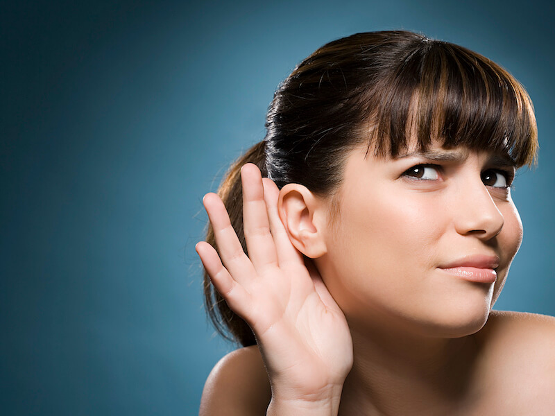 Woman cupping ear and grimacing because of single sided hearing loss