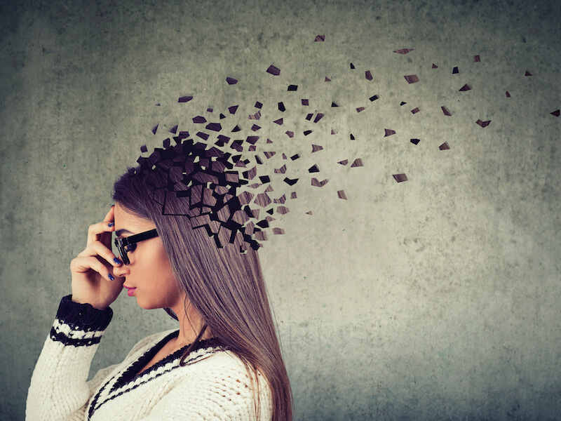 Woman with long dark hair and black rimmed glasses experiencing cognitive decline.
