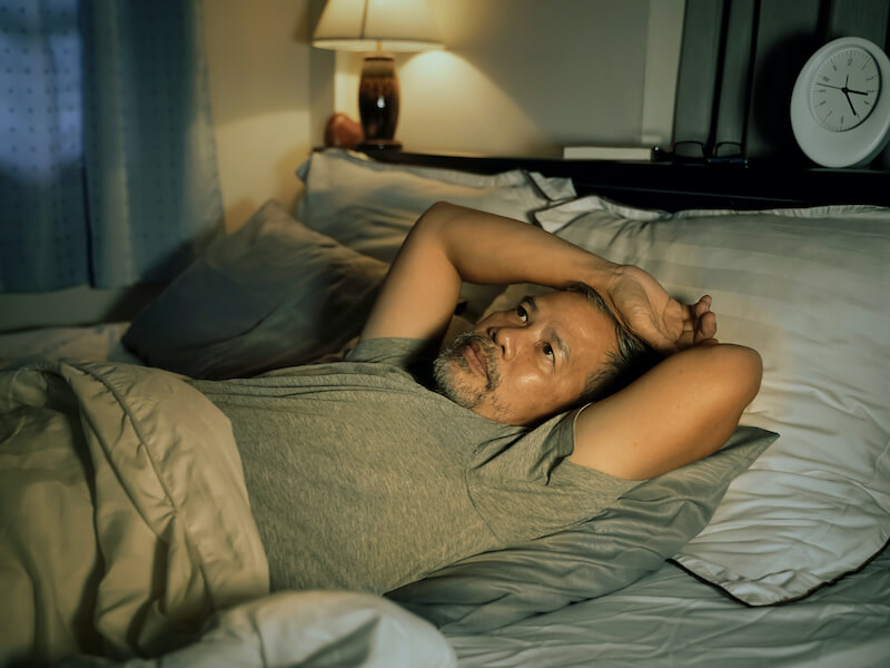Man with hearing loss lying in bed suffering from insomnia