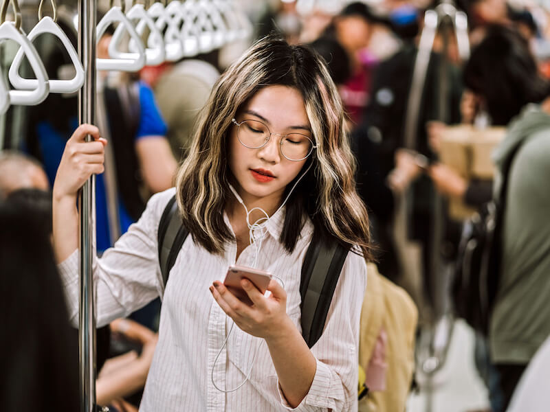 Young woman not protecting her hearing in a loud subway.
