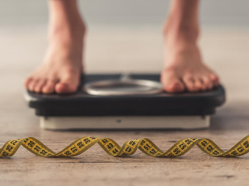 Woman weighing herself and realizing her weight affects her hearing health.