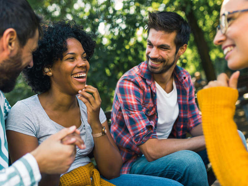 Woman with hearing loss wearing hearing aids having fun with her friends in the park.
