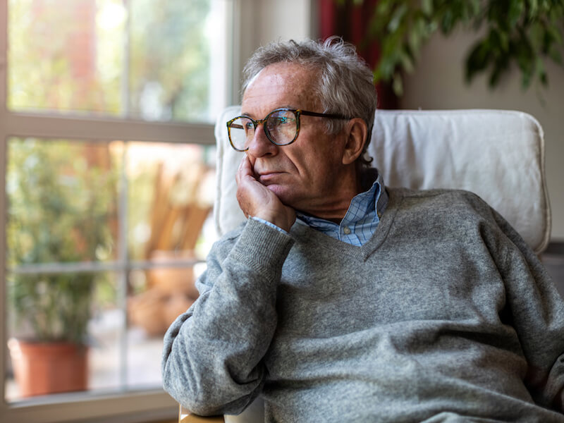 Man with untreated hearing loss depressed and looking out the window.