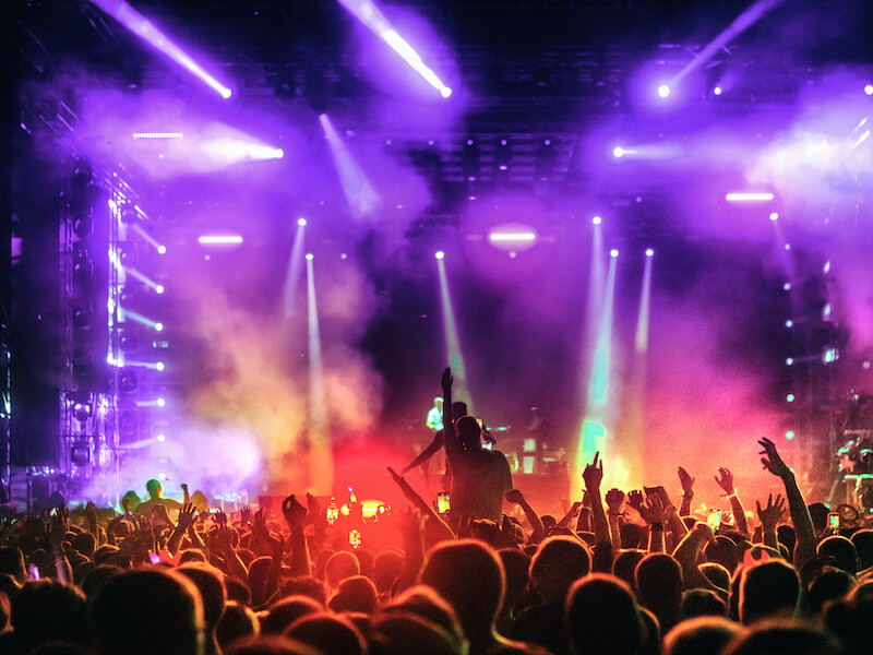 Large summer concert crowd of people in front of a stage at night who should be concerned about hearing protection