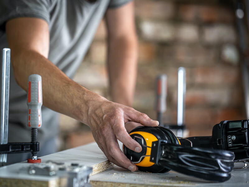 Professional carpenter workplace with protective headphones, personal protection for work at woodwork production workshop.