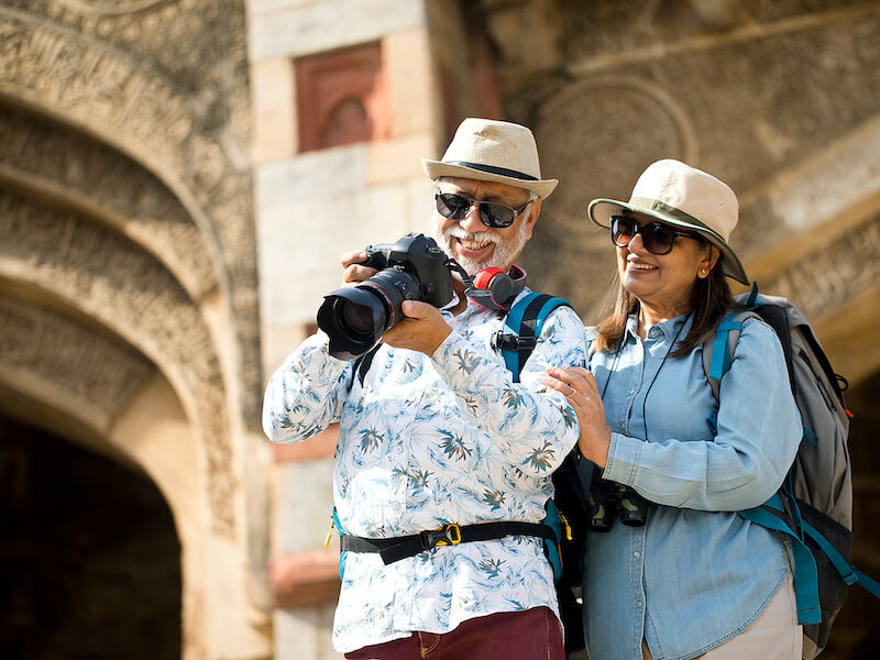 Senior couple with hearing loss watching photos from travel on digital camera during vacation